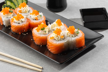 Philadelphia roll sushi with salmon, avocado, cream cheese and red caviar. Sushi menu. on dark plate. Traditional japanese seafood, healthy food concept. Top view horizontal photo on white background.