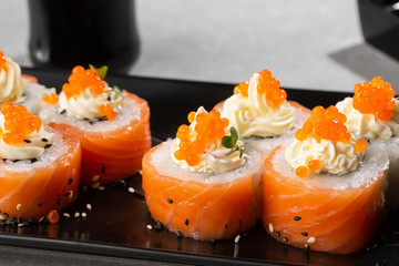 Philadelphia roll sushi with salmon, avocado, cream cheese and red caviar. Sushi menu. on dark plate. Traditional japanese seafood, healthy food concept. Top view horizontal photo on white background.