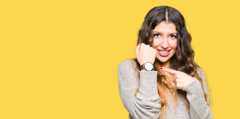 Young beautiful woman wearing winter dress In hurry pointing to watch time, impatience, upset and...