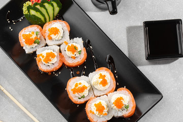 Philadelphia roll sushi with salmon, avocado, cream cheese and red caviar. Sushi menu. on dark plate. Traditional japanese seafood, healthy food concept. Top view horizontal photo on white background.