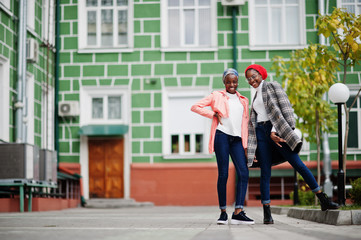 Two young modern fashionable, attractive, tall and slim african muslim womans in hijab or turban head scarf and coat posed.
