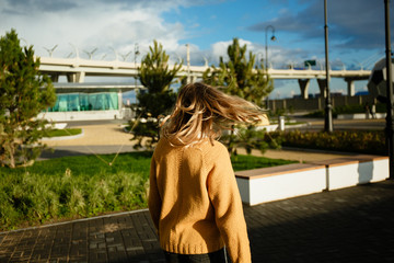 Fototapeta na wymiar Blonde girl with bursting aolos in a yellow sweater against the backdrop of the city