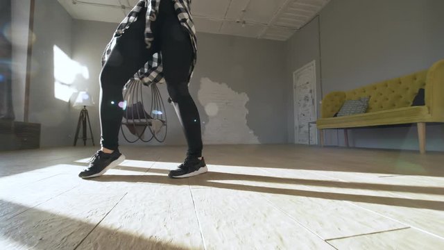 Tracking shot of beautiful young female house dancer moving to music in sunny studio