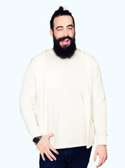 Young man with long hair and beard wearing sporty sweatshirt winking looking at the camera with sexy expression, cheerful and happy face.