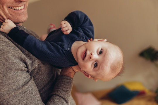 Baby wird von einem Mann gehalten und streckt den Nacken durch