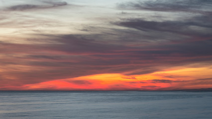 Beautiful Summer landscape sunset image of colorful vibrant sky over calm long exposure sea