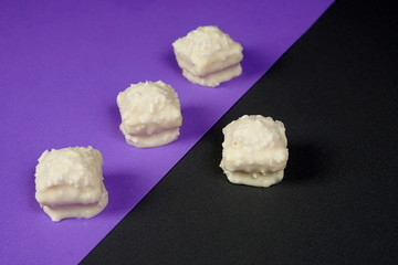 A few chocolates with nuts and white chocolate on a purple-gray background