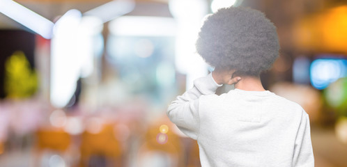 Young african american man with afro hair wearing sporty sweatshirt Backwards thinking about doubt with hand on head