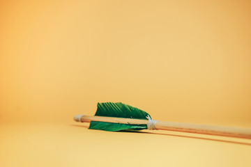 Old green wooden arrow on a beautiful YELLOW background.