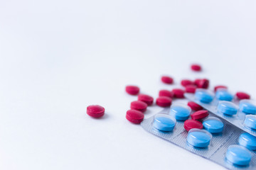 Red and blue pills on white background. Scattered red pills next to blue pills in blisters