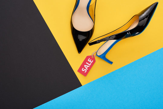 top view of elegant shoes with sale label on blue, yellow and black background