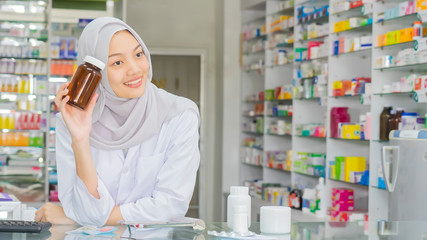Muslim female pharmacist working in a small drugstore.
