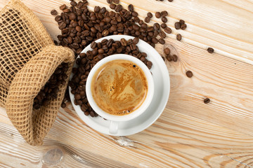 Hot coffee cup and coffee beans on brown background top view