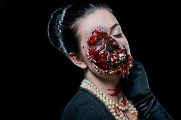 Woman with horror make up in the studio on a black background. Halloween make up. Zombie.
