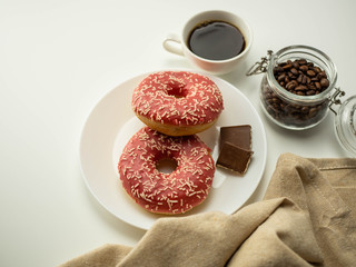 Różowy donut z posypką. Kawa i czekolada. Widok z góry, jasne tło.