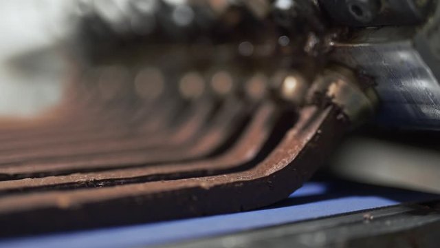 Close-up handheld shot of a chocolate bars coming out of a machine in a candy and chocolate factory