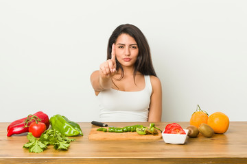 Young curvy woman preparing a healthy meal showing number one with finger.