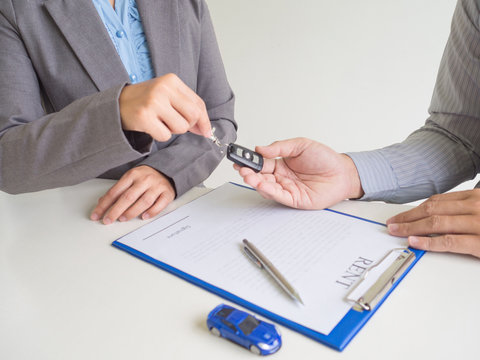 Car saleswoman giving the key to customer and signed a car rent service lease contract