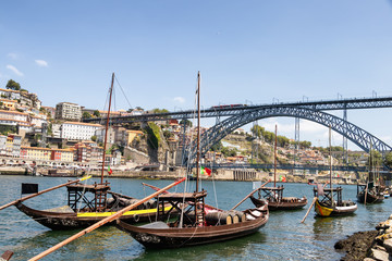 Fototapeta na wymiar Porto and old traditional boats with wine barrels in Portugal with Dom Luis I Bridge in the background