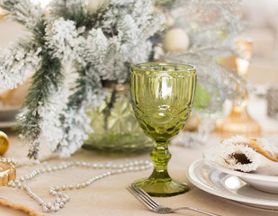 Image of Christmas dinner in home, Christmastime table setting over decorated fir tree background, glass for champagne