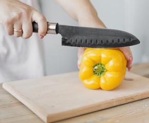 Pregnant woman cutting a yellow pepper