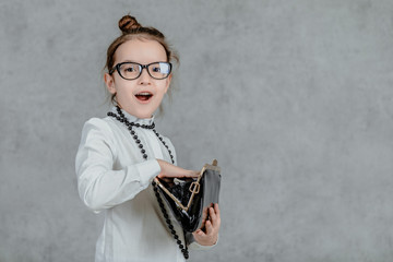 Small business lady child is on a gray background. Holds a bag in his hands. Black necks are on the neck.