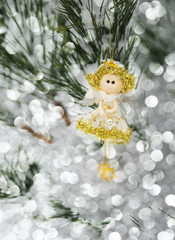 Little decorative fairy on pine tree with snow and bokeh. lights.