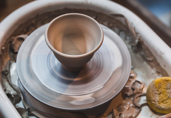 A pot of light clay on a potter's wheel. Close-up. Selective focus.
