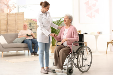 Fototapeta na wymiar Nurse assisting elderly woman in wheelchair indoors