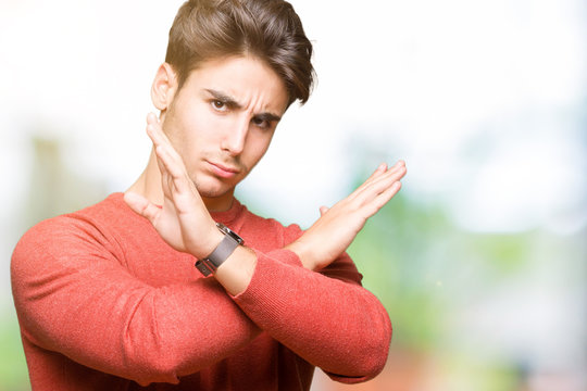 Young handsome man over isolated background Rejection expression crossing arms doing negative sign, angry face