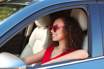 Fototapeta na wymiar Young beautiful African-American woman wearing heart shaped glasses in car