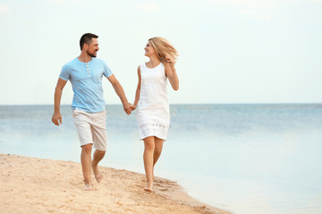 Happy romantic couple running together on beach, space for text