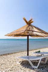 Two loungers and umbrella on a beach.