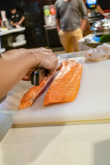 Chef preparing and cutting  fresh salmon in Japanese restaurant