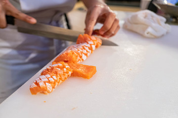 Chef preparing and cutting  fresh salmon in Japanese restaurant