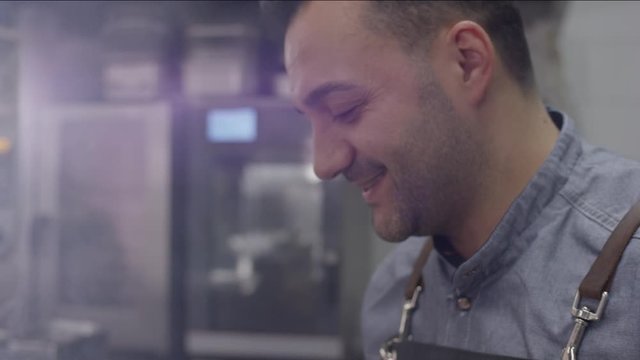 close up of a chef of an upscale restaurant kitchen joyfully indulging in his craft - Close Up des Gesichtes eines K&uuml;chenchefs der mit Freude am Kochen ist in einer gehobenen K&uuml;che
