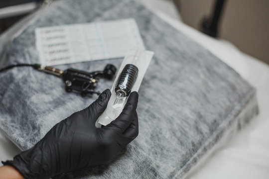 machine for permanent makeup in the hand of the master in a black glove and a disposable needle 1