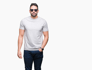 Young handsome man wearing sunglasses over isolated background with a confident expression on smart face thinking serious