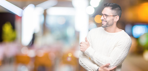 Young handsome man wearing glasses over isolated background Looking proud, smiling doing thumbs up gesture to the side