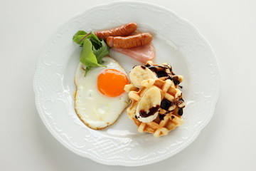 Homemade banana and chocolate waffle with sunny side up egg