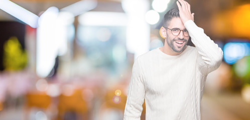 Young handsome man wearing glasses over isolated background surprised with hand on head for...