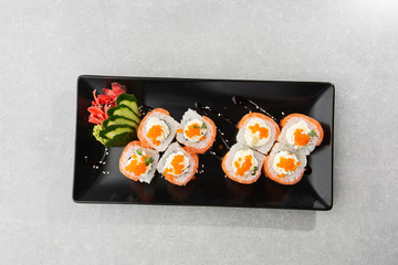 Philadelphia roll sushi with salmon, avocado, cream cheese and red caviar. Sushi menu. on dark plate. Traditional japanese seafood, healthy food concept. Top view horizontal photo on white background.