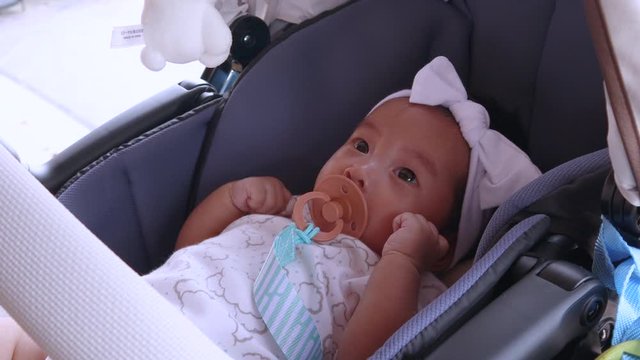 4k Asian 3 months baby in baby car and pacifier, day time, hot day, feeling happy, natural sun light shade