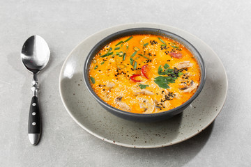 Tom Yam kung Spicy Thai soup with shrimp, seafood, coconut milk and chili pepper in bowl. In gray stone background. Horizontal photo.