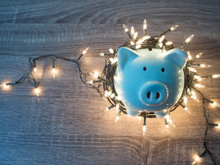 Blue piggy bank with Christmas string lights on happy December festival, Enjoy savings for spending...