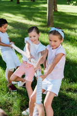 selective focus of happy multicultural children competing in tug of war