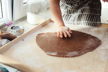 Obraz premium Anonymous child's hands cutting festive shapes out of gingerbread cookie dough.