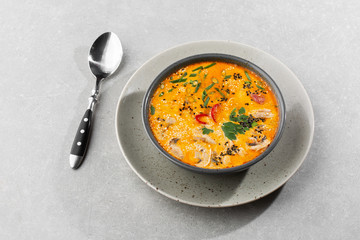 Tom Yam kung Spicy Thai soup with shrimp, seafood, coconut milk and chili pepper in bowl. In gray stone background. Horizontal photo.