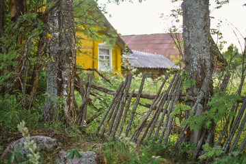 Old wooden broken fence on a background of a yellow house