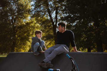 Father and son sitting on a skate ramp and talking